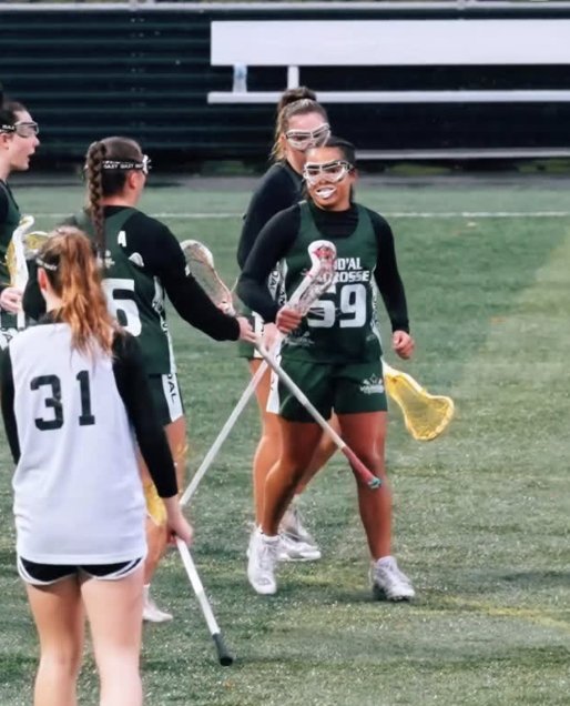 Freya Larson smiling in her Vand'al Lacrosse uniform, number 59, on the field with teammates