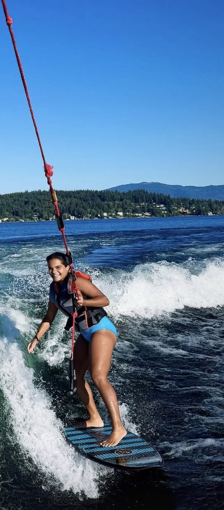 Freya Larson on the tow rope, wakesurfing on Lake Sammamish and grinning at the camera